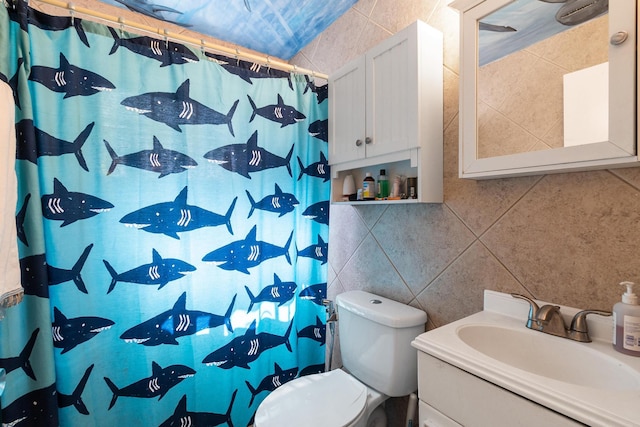 bathroom featuring tile walls, toilet, and vanity