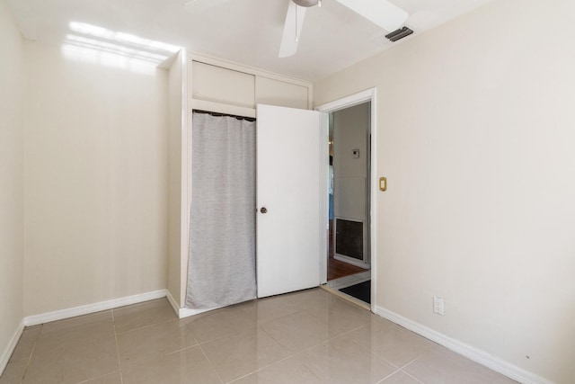 unfurnished bedroom with light tile patterned flooring, ceiling fan, and a closet