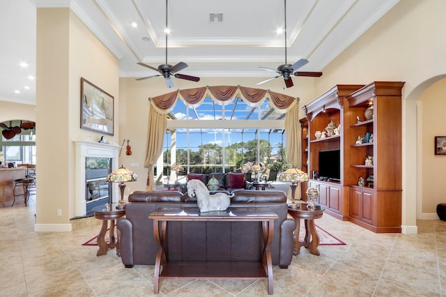 tiled living room with ceiling fan, a high ceiling, and a tray ceiling