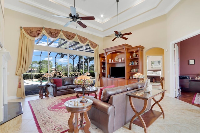 tiled living room featuring ceiling fan, a high ceiling, and ornamental molding