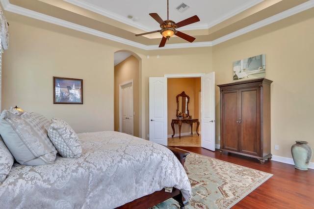 bedroom featuring a raised ceiling, ceiling fan, crown molding, and dark hardwood / wood-style flooring