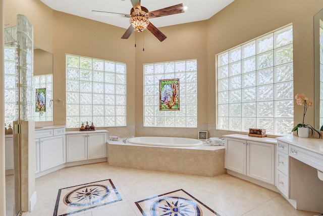 bathroom with tile flooring, oversized vanity, ceiling fan, and tiled bath