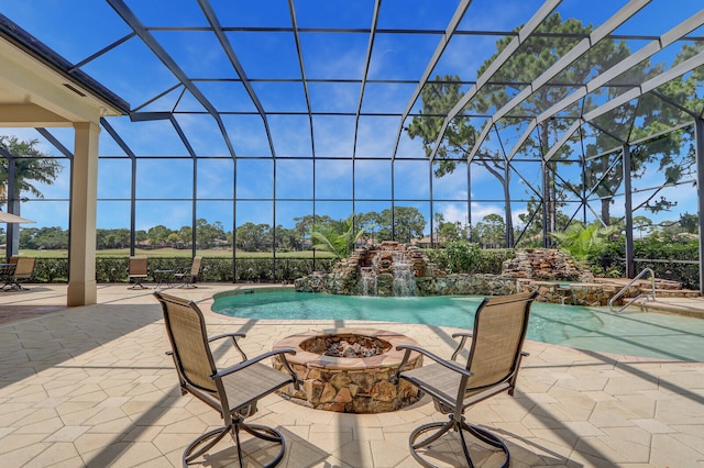 view of pool featuring a patio area, pool water feature, an outdoor fire pit, and a lanai