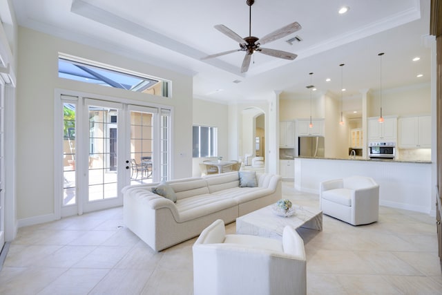 tiled living room featuring french doors, ornamental molding, ceiling fan, and a raised ceiling