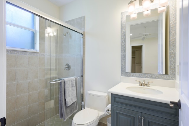 bathroom with a shower with shower door, large vanity, ceiling fan, and toilet