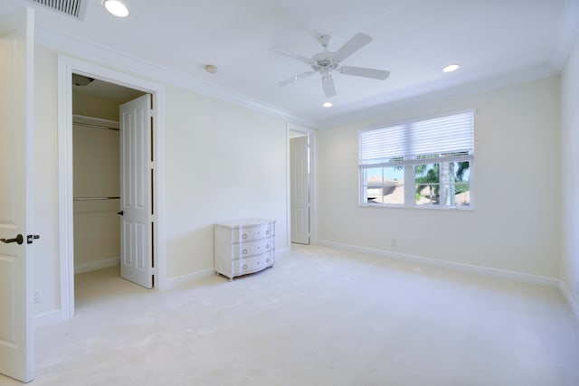 unfurnished bedroom featuring a closet, ceiling fan, crown molding, a walk in closet, and light colored carpet