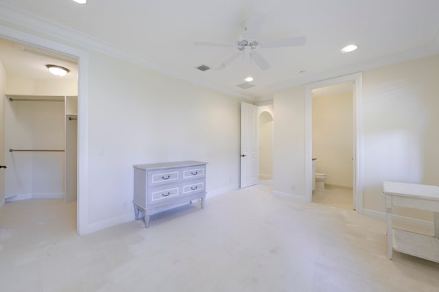 bedroom with ceiling fan, a closet, a spacious closet, ensuite bath, and ornamental molding