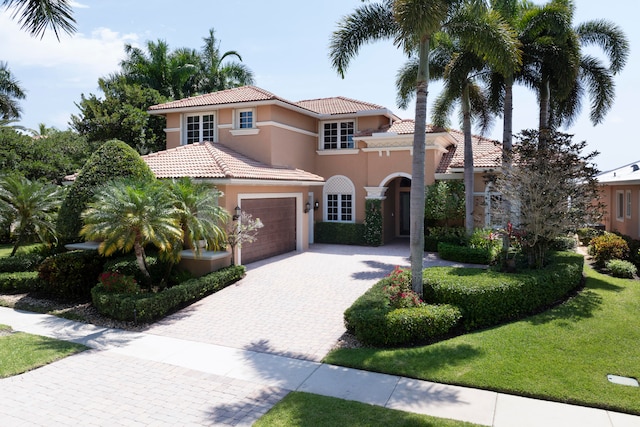 mediterranean / spanish-style home featuring a front lawn and a garage