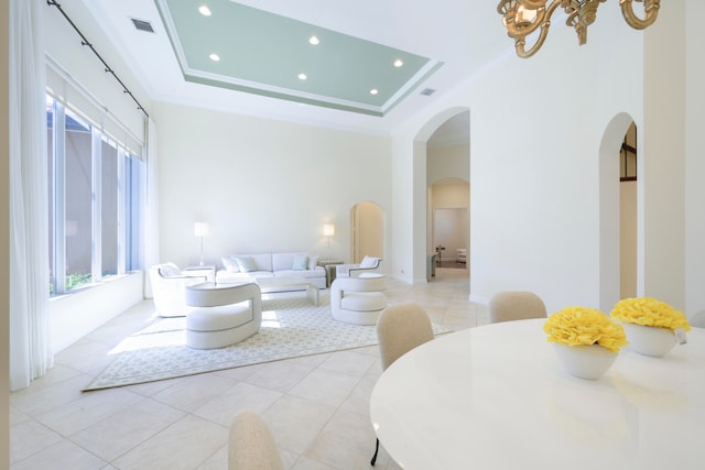 tiled living room featuring ornamental molding and a raised ceiling