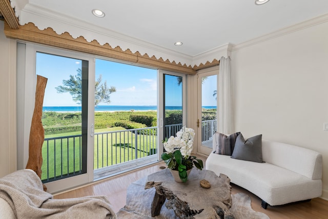 living room with a water view, a wealth of natural light, wood-type flooring, and ornamental molding