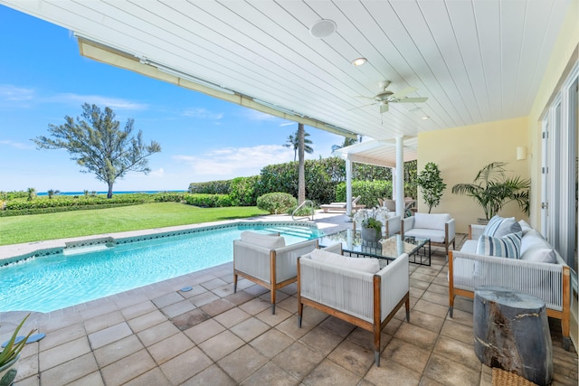 view of pool with an outdoor living space, a yard, ceiling fan, and a patio area