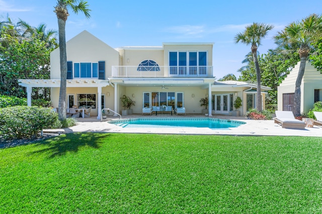 rear view of property with a patio, a yard, and a balcony