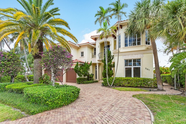 mediterranean / spanish-style home featuring a garage and a balcony