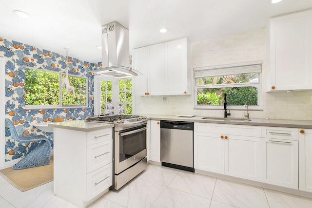 kitchen with tasteful backsplash, island range hood, light tile floors, sink, and appliances with stainless steel finishes