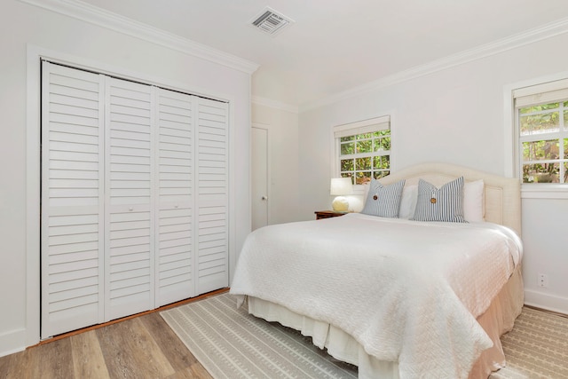 bedroom with hardwood / wood-style floors, ornamental molding, a closet, and multiple windows