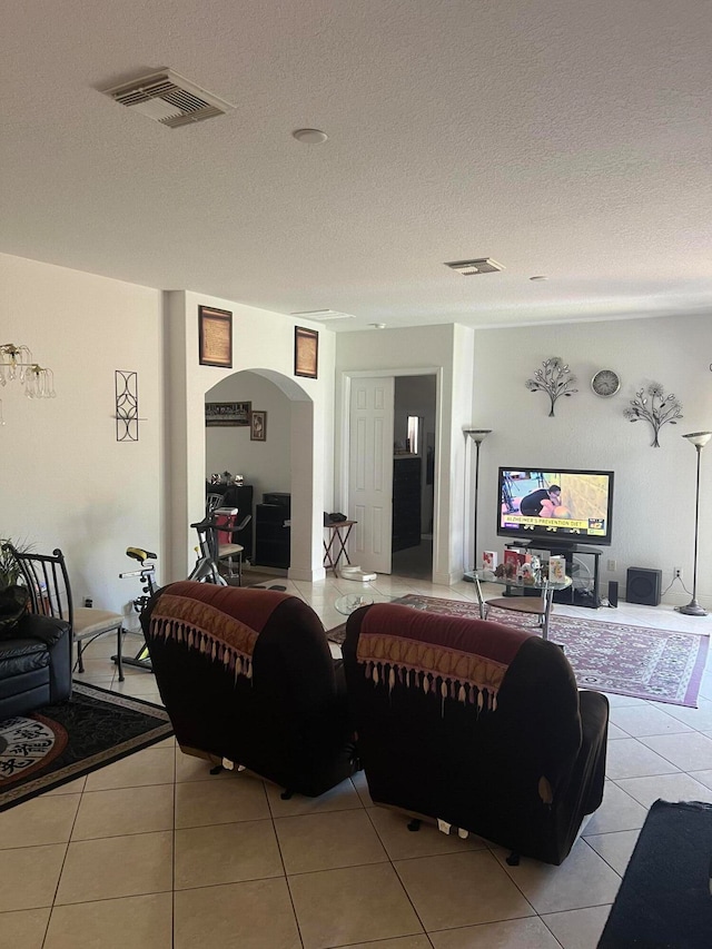 living room with a textured ceiling and light tile floors