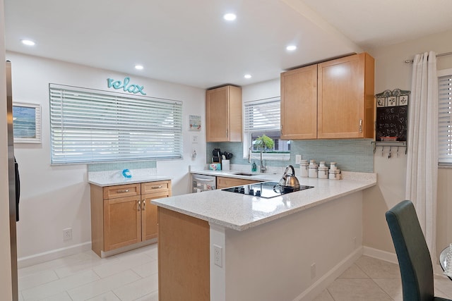 kitchen with kitchen peninsula, black electric cooktop, light stone countertops, and sink