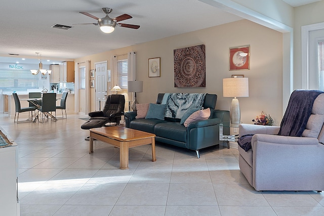 tiled living room featuring a textured ceiling and ceiling fan with notable chandelier