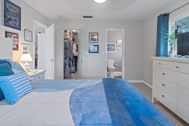 bedroom featuring light tile patterned floors, a spacious closet, connected bathroom, and a closet