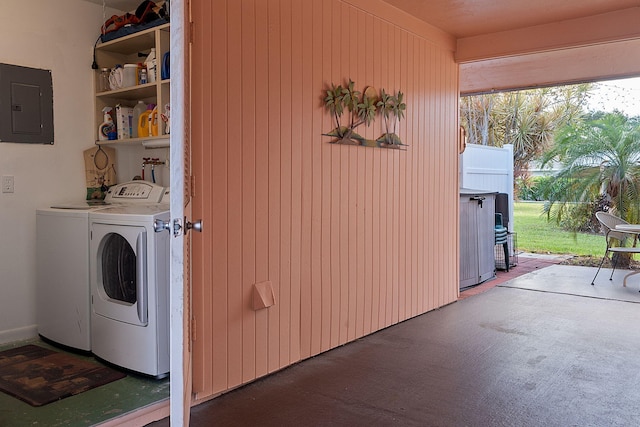 laundry room with washer and clothes dryer, wooden walls, and electric panel