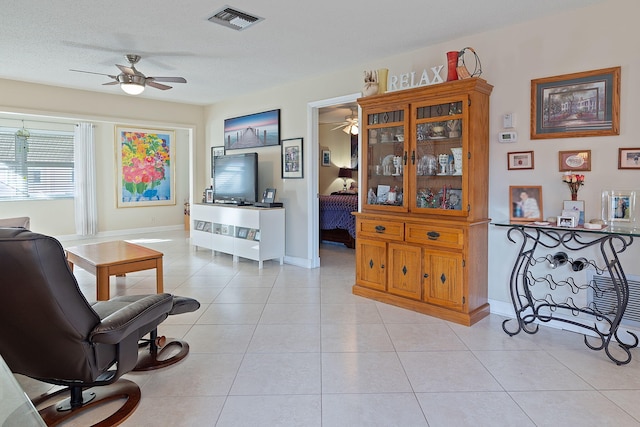 living room featuring light tile patterned floors, a textured ceiling, and ceiling fan