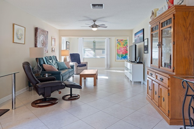 living room featuring light tile patterned floors, a textured ceiling, and ceiling fan