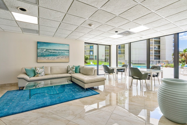 living room with tile flooring, expansive windows, and a paneled ceiling