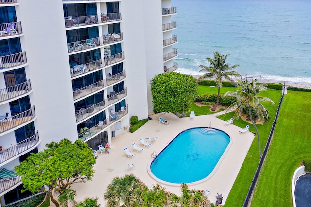 view of swimming pool featuring a yard and a water view