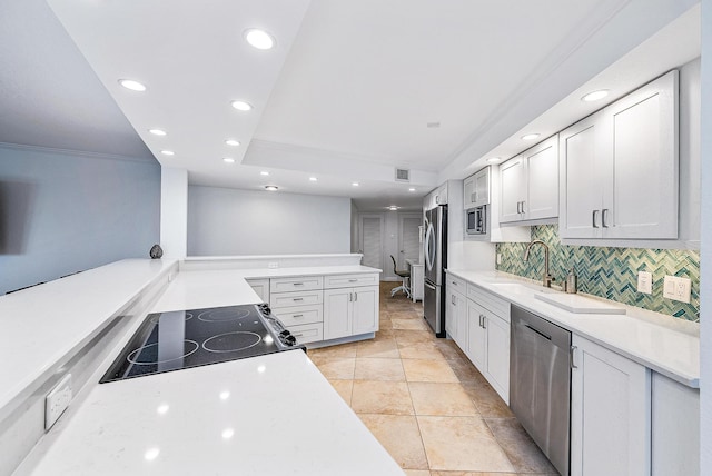 kitchen with light tile floors, tasteful backsplash, a raised ceiling, white cabinetry, and stainless steel appliances