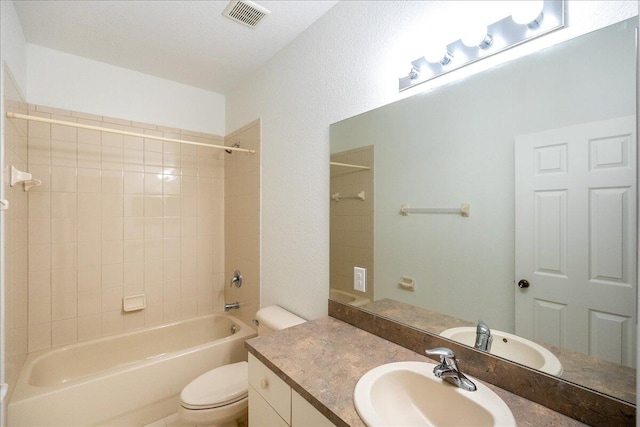 full bathroom with tiled shower / bath, toilet, oversized vanity, and a textured ceiling