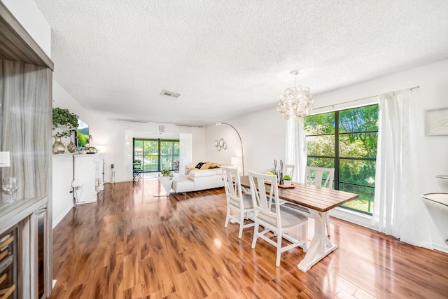 dining space with a textured ceiling, dark hardwood / wood-style flooring, and a notable chandelier