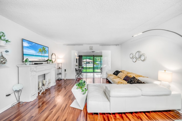 living room featuring wood-type flooring, a textured ceiling, and a chandelier