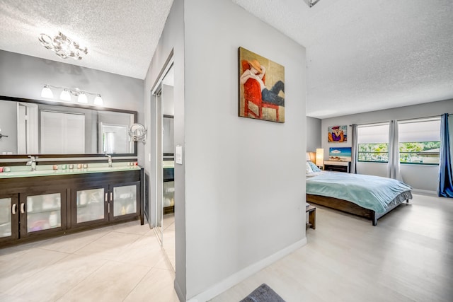 tiled bedroom featuring a closet, a textured ceiling, and ensuite bathroom