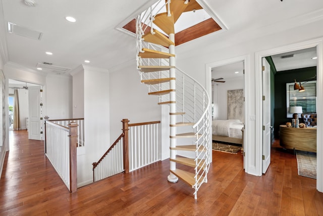 stairs with crown molding and wood-type flooring