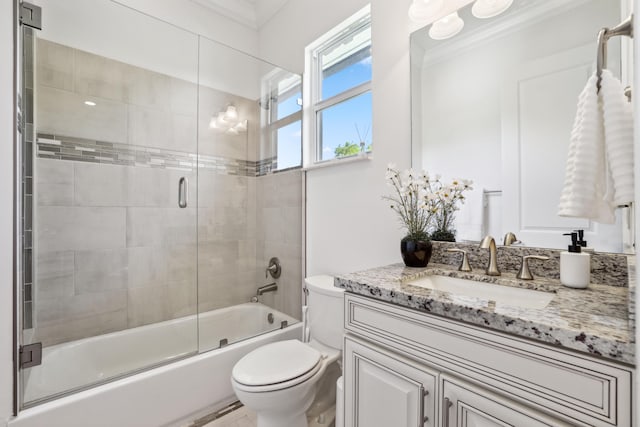 full bathroom featuring combined bath / shower with glass door, toilet, crown molding, and vanity