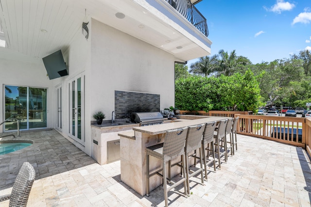 view of patio featuring a grill, a balcony, an outdoor kitchen, and a wet bar