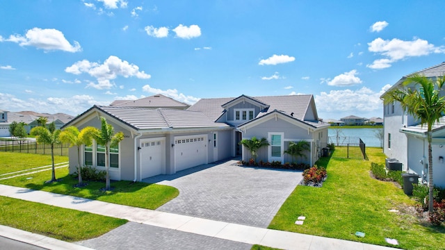 view of front of house featuring a garage, a water view, central air condition unit, and a front yard