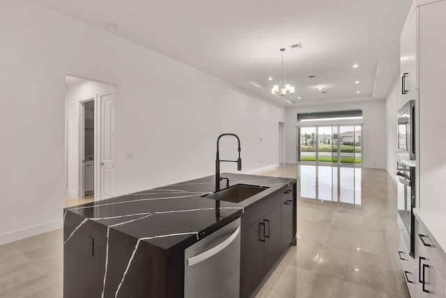 kitchen featuring sink, hanging light fixtures, appliances with stainless steel finishes, a tray ceiling, and a kitchen island with sink