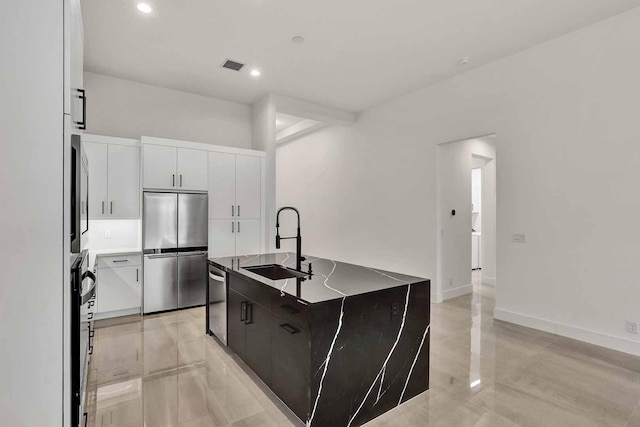 kitchen featuring a kitchen island with sink, sink, stainless steel appliances, and white cabinets