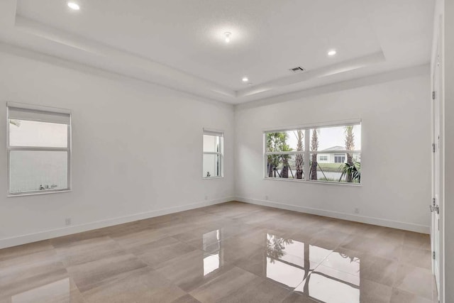 tiled spare room featuring a tray ceiling