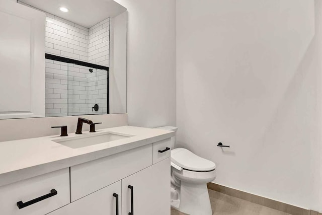 bathroom with vanity, toilet, and a shower with door