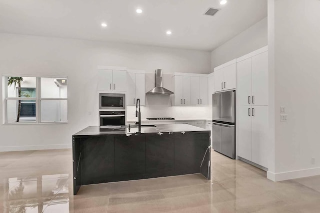 kitchen featuring white cabinets, stainless steel appliances, sink, an island with sink, and wall chimney exhaust hood