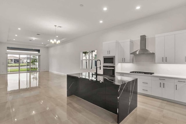 kitchen featuring stainless steel microwave, decorative light fixtures, white cabinets, oven, and wall chimney range hood