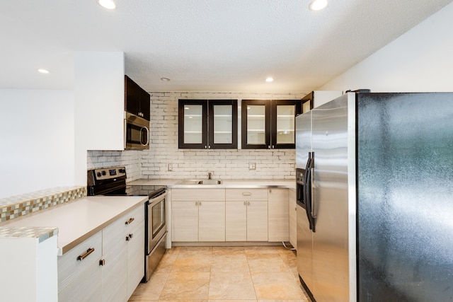 kitchen with sink, appliances with stainless steel finishes, backsplash, and light tile floors