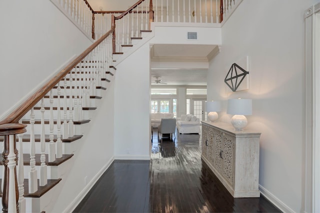 stairway with wood-type flooring, ceiling fan, and a high ceiling