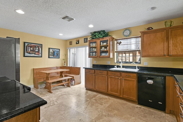 kitchen featuring black dishwasher, sink, a textured ceiling, and stainless steel refrigerator