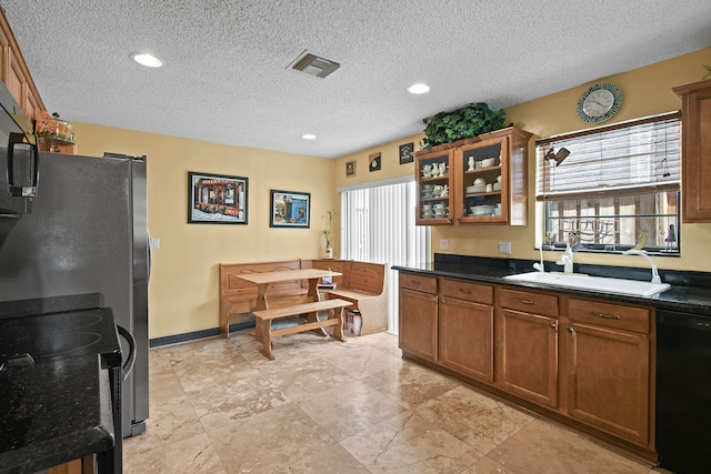 kitchen featuring a textured ceiling, black appliances, and sink