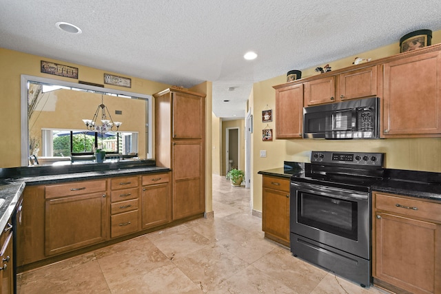 kitchen with an inviting chandelier, stainless steel appliances, and a textured ceiling