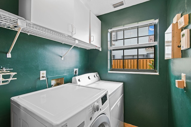 washroom with washer and dryer and cabinets