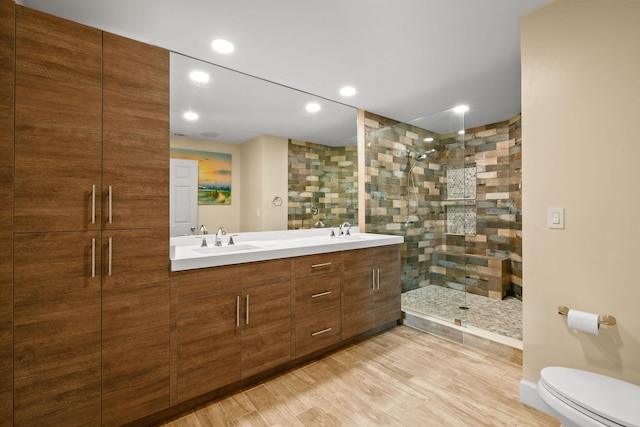 bathroom with a shower with shower door, hardwood / wood-style flooring, vanity, and toilet